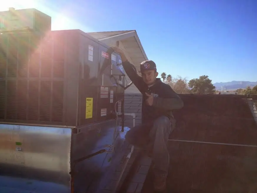 HVAC technician performing AC Tune-Up on a rooftop unit in Defiance